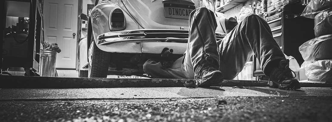 Mecánico arreglando los bajos de un coche