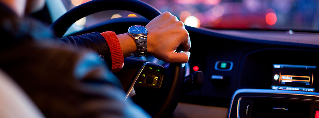 Vista del interior de un coche con una mano sobre el volante