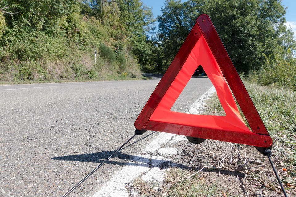 Triangulo rojo de emergencia sobre línea blanca de carretera.