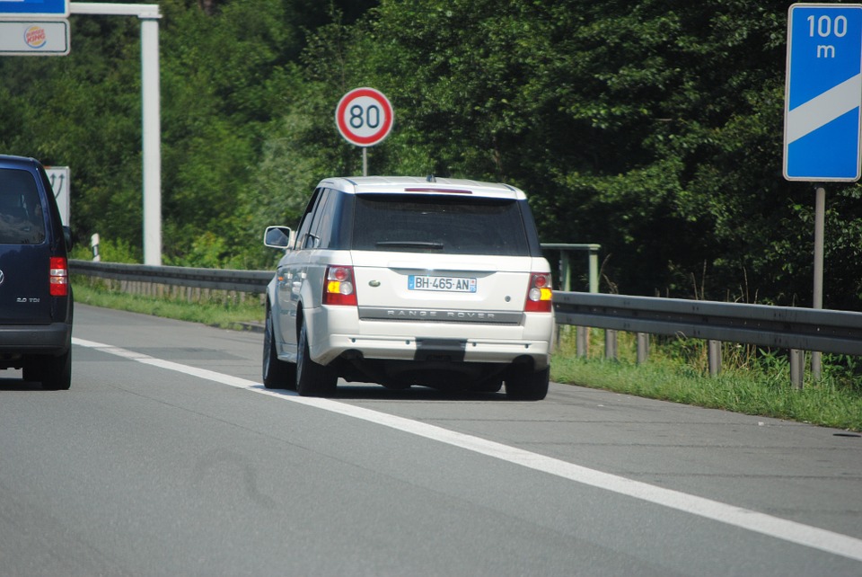 Coche pequeño blanco en arcén de carretera junto línea blanca del margen.