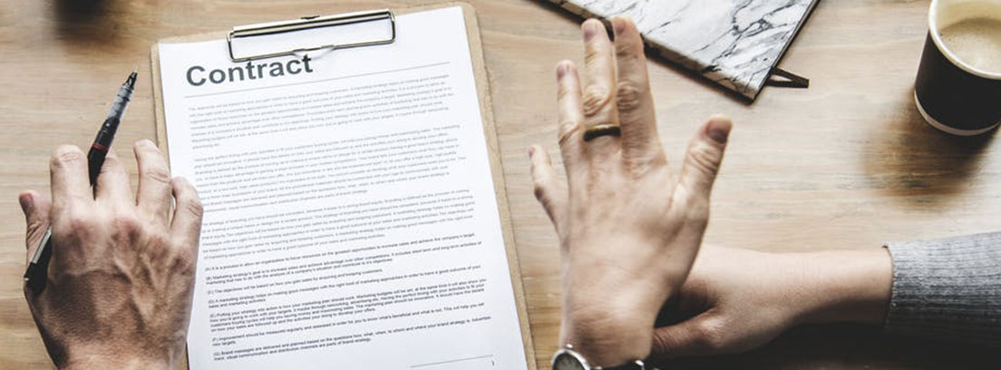 Trucos para preparar un contrato de compraventa Sobre una mesa carpeta con papeles escritos mano con boli y reloj delante