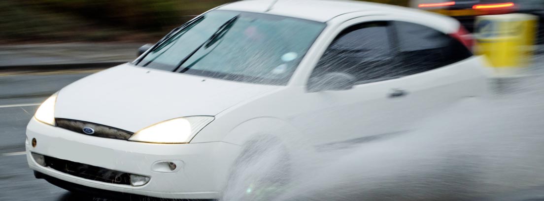 Coche en situación de aquaplaning circulando por una carretera con agua
