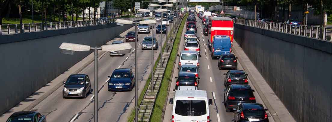 Carretera de doble sentido con mediana central y llena de coches