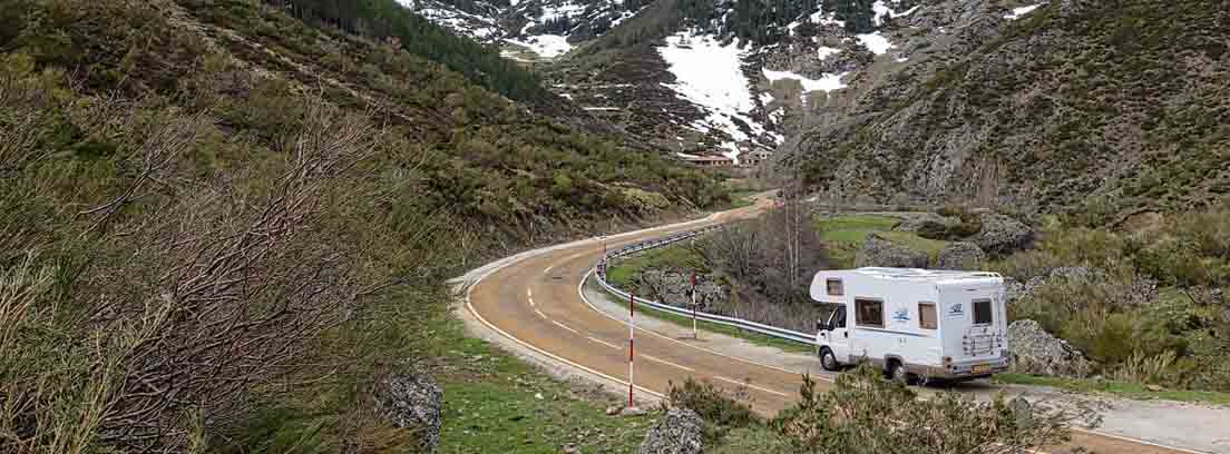 Caravana blanca de ruta por nuestro país Caravana blanca por carretera entre montes y con fondo de montaña nevada
