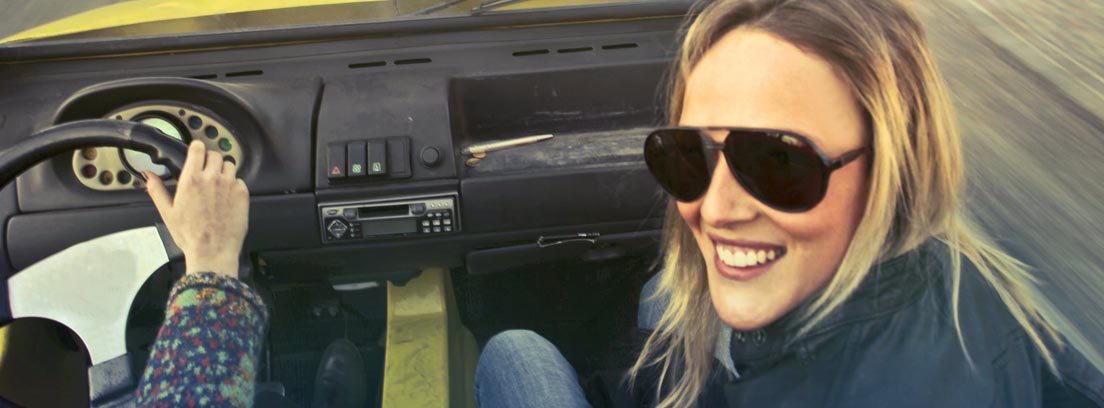 Mujer con gafas de sol dentro de coche y junto a conductor