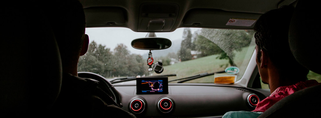 Vista interior de coche con dos personas dentro y gps con pantalla y cámara en el cristal