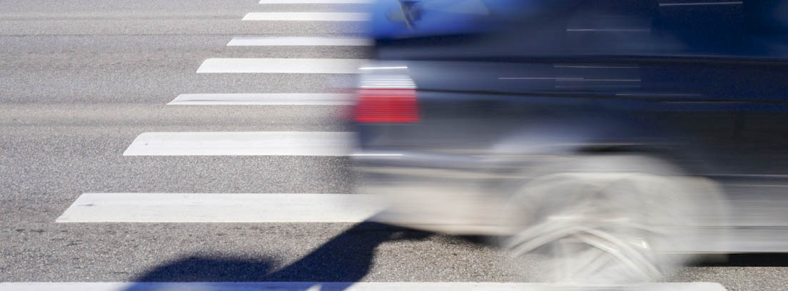 Imagen borrosa de un coche pasando por encima de un paso de peatones