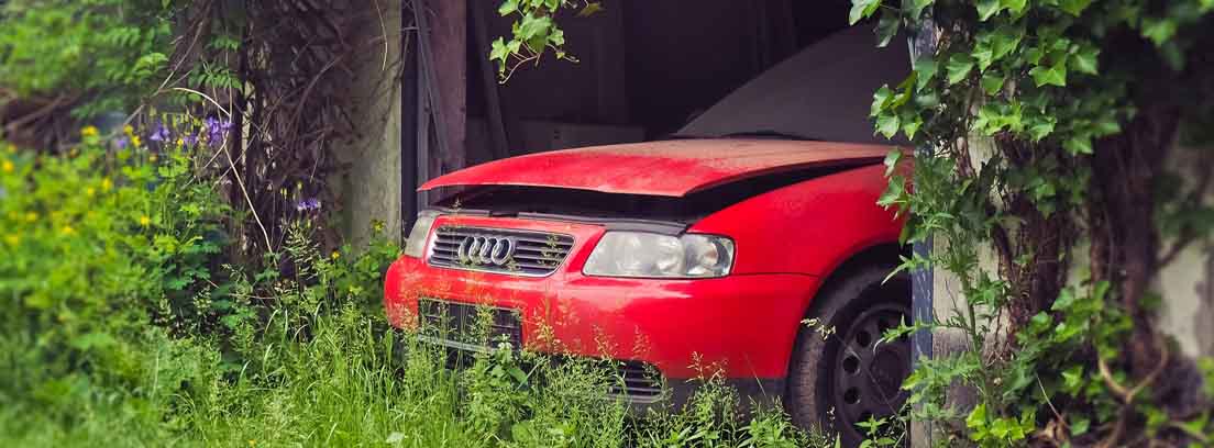coche rojo estropeado abandonado en un cobertizo
