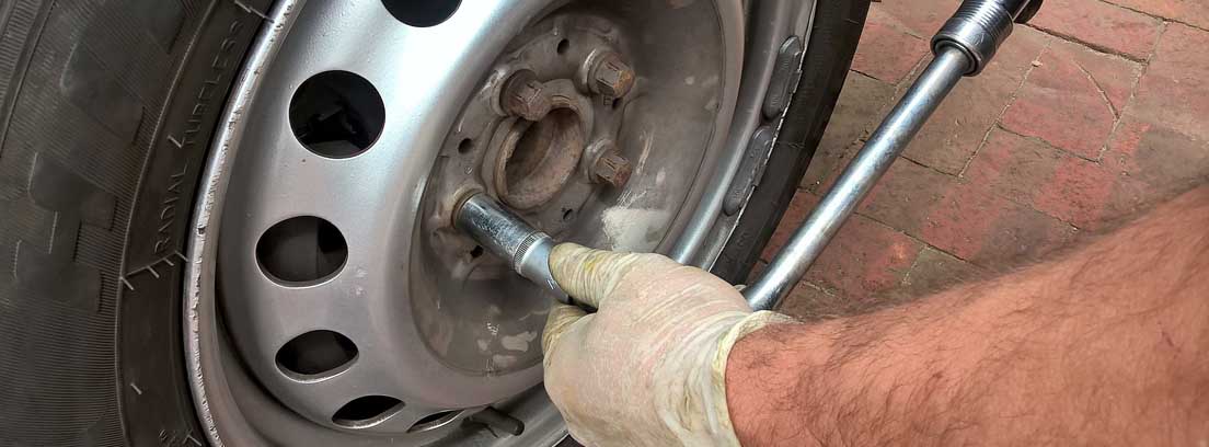 Mano con herramienta desmontando una rueda antes de pintar pinzas de freno