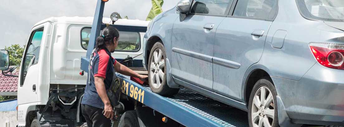 Mujer al lado de una grúa con un coche