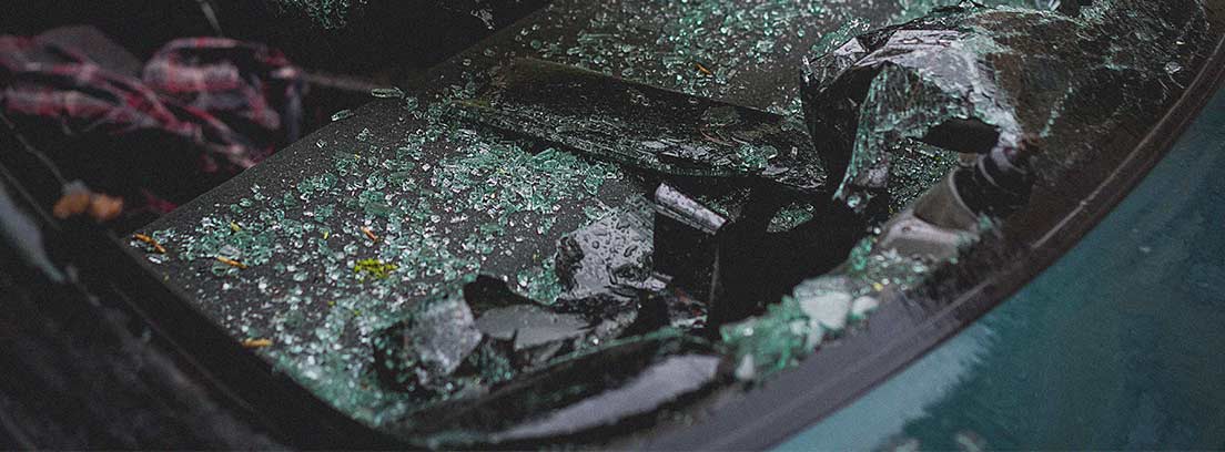 Luna delantera de coche rota y cristales dentro del vehículo