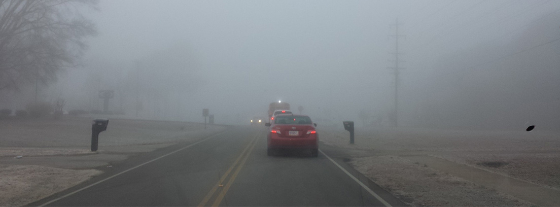 Coches circulando por una carretera con niebla